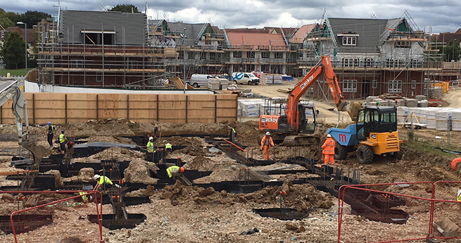 Mackoy Groundworks Site Overview with Groundworkers Preparing Foundations for Concrete Pour and Plant Machinery on Site