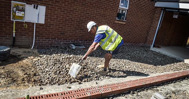 Mackoy Groundworker Levelling Stones Before Surfacing