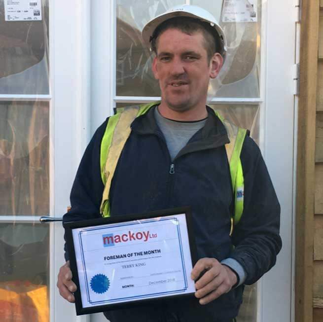 Foreman of the month December holding his award standing in front of house