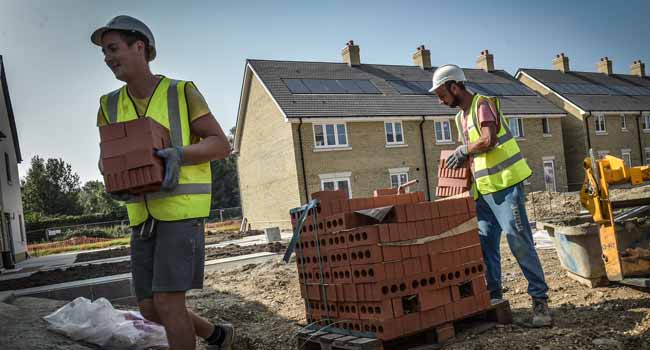 Groundworkers moving red bricks on construction site